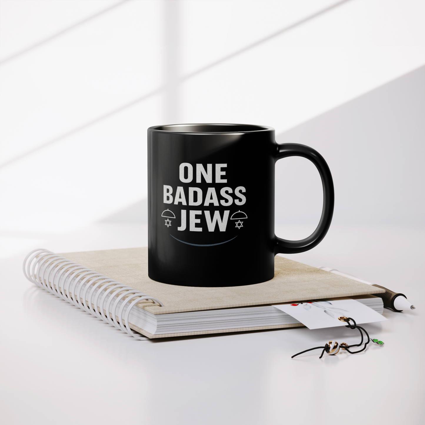 One_Badass_Jew_Black_Mug_11oz_Lifestyle_Notebook_Mockup.png