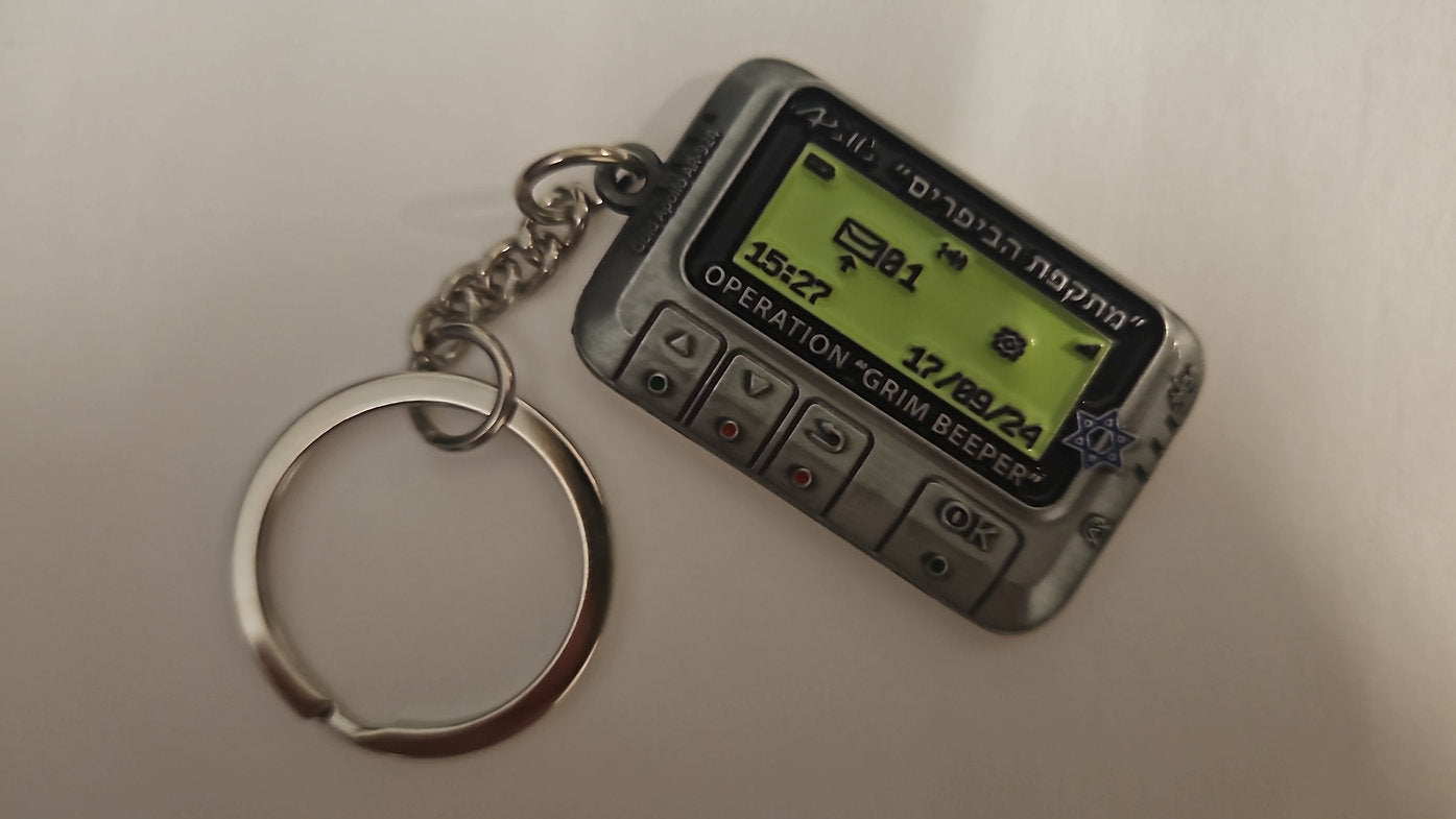 Small replica of an electronic device with a digital display on a keychain, on a plain background