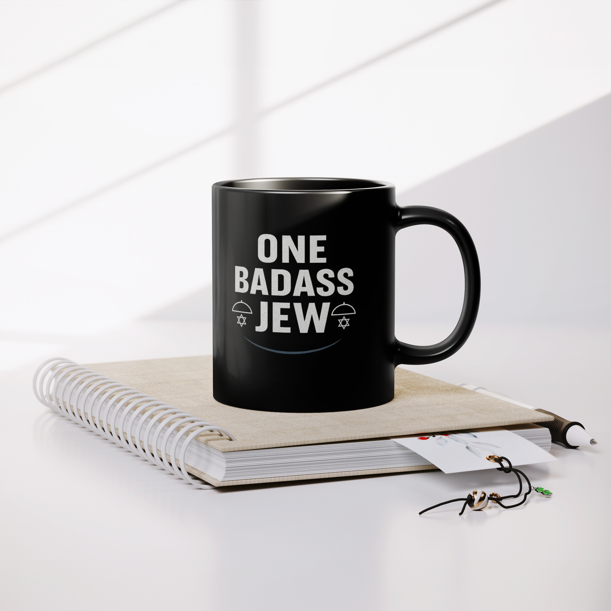 One_Badass_Jew_Black_Mug_11oz_Lifestyle_Notebook_Mockup.png