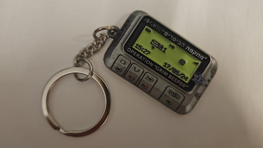 Small replica of an electronic device with a digital display on a keychain, on a plain background